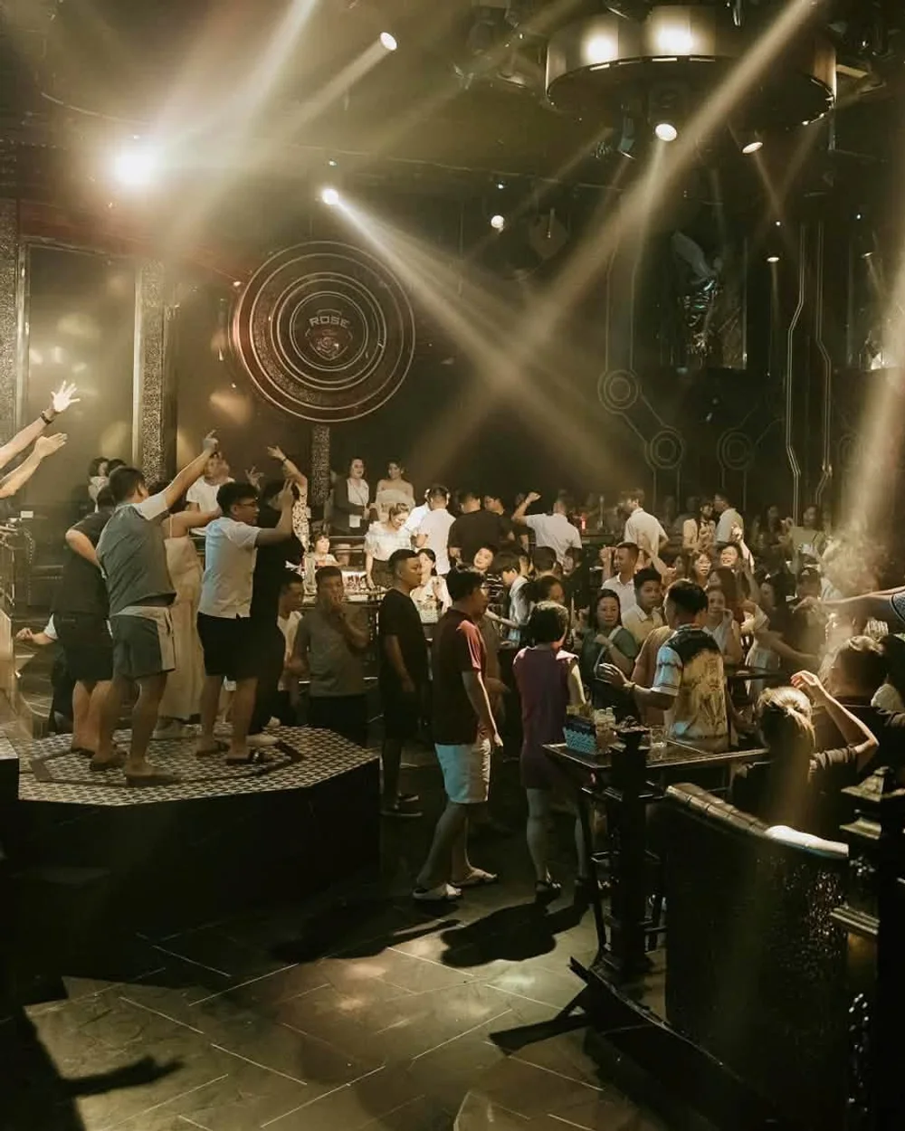 Tia đèn quét qua sàn và đĩa huy hiệu ROSE sau sân khấu tại Rose Club Cát Bà